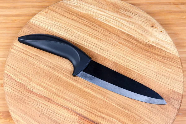 Ceramic multipurpose black kitchen knife on wooden cutting board