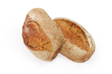 Beyaz arka planda kepekli ve mayasız iki somun ekmek.