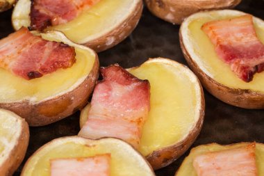 Pastırma dilimleri ile pişirilmiş tenlerinde patates parçaları, seçici bir odak noktasında parça parça.