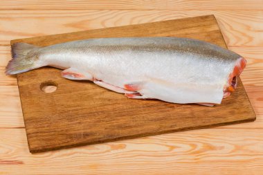 Köy masasındaki ahşap kesim tahtasının üzerinde kafası olmadan pişmemiş taze kutup kirişinin tüm leşi.