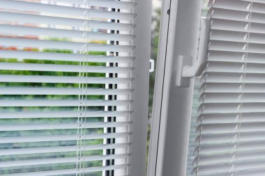 Modern eğimin bir parçası ve plastik pencereyi kontrol kolu ve beyaz yatay jaluziler ile içe doğru eğimli, içeriden görüşlü, seçici odaklı,