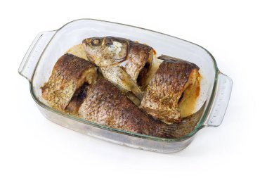 Beyaz arka planda pişirmek için cam tavada baharatlarla pişirilmiş sazan balıkları.