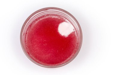 İçinde çözünmüş bir bardak su. Fışkıran ecza ürünü tableti. Işık yüzeyinin en üst görüntüsü.  