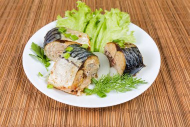 Kurutulmuş Atlantik uskumrusu, marul, soğan ve yeşillikler bambu hasırında beyaz tabakta.