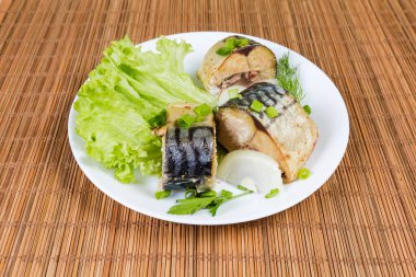 Kurutulmuş Atlantik uskumrusu, marul, soğan ve yeşillikler bambu hasırında beyaz tabakta.