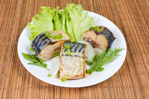 Kurutulmuş Atlantik uskumrusu, marul, soğan ve yeşillikler bambu hasırında beyaz tabakta.