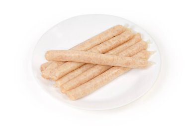 Beyaz arka planda beyaz tabakta çiğ, uzun tavuk sosisi.