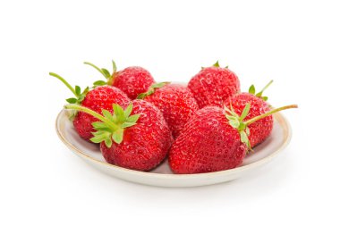 Beyaz arka planda bir fincan tabağında kuyrukları olan taze olgun çilekler seçici bir odak noktasında yakın plan.