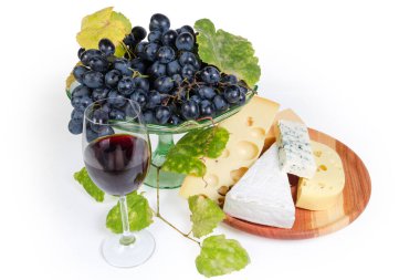 Çeşit çeşit peynir, bir bardak kırmızı şarap, taze mavi üzüm.