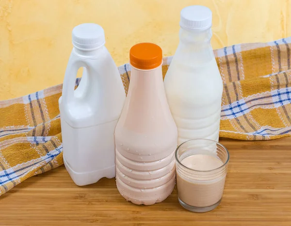 Bardakta Mayalanmış Süt Ile Çeşitli Süt Ürünlerinin Plastik Şişelerine Karşı — Stok fotoğraf