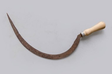 Eski paslı orak, ince tırtıklı, yarı dairesel bıçak ve tahta saplı, açık bir yüzey, üst manzara.