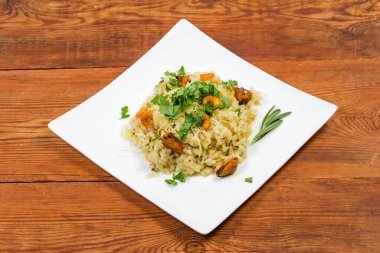 Balık suyunda pilavlı pilav servis ediyorum. Eski kırsal masada, beyaz bir tabakta deniz ürünleri ile birlikte.