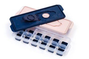 Bir açık ve bir kapalı ev tepsisi beyaz arka planda buz küpü yapmak için farklı renkler sunar.