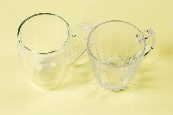 Dois Copos Vidro Transparentes Vazios Diferentes Com Alças Uma Superfície — Fotografia de Stock