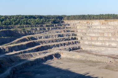 Ormanlar arasında gri granitin çıkarılması için çalışan taş ocakları yaz sabahları çıkıntılı yamaçlar.