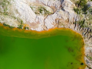 Renkli gölün bir kısmı ve terk edilmiş ilmenit taş ocağının bulunduğu yerdeki eski atık kaya yığınları, dikey hava manzarası.