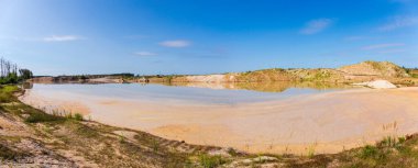 Gökyüzüne karşı ilmenit taş ocağı işletiminde maden lehine çalışan bir tarağın sonucu olarak ortaya çıkan sığ teknolojik göl, panoramik görüş