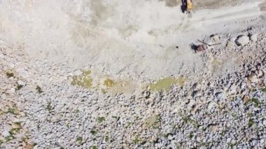 Taş ocağındaki maden makineleri yaz günü dikey hava manzaralı gri granitin çıkarılması için çalışıyor.