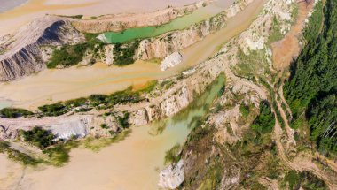 Ormanın kıyısındaki terk edilmiş ilmenit taş ocağının olduğu yerde, eski atık kayaların arasında renkli göller ortaya çıktı.
