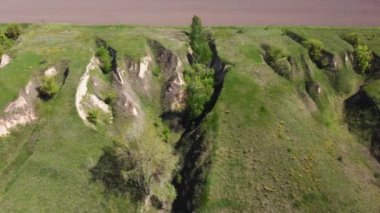 Vadi yamaçlarında çimlerle kaplanmış dik vadiler ve tarıma karşı tek ağaçlarla kaplı arka planda, yamaçtan yukarı çıkarken hava manzarası