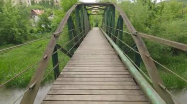 Nehrin üzerinde ahşap güverteli metal bir köprü.