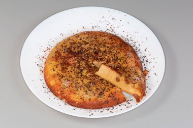 Kuru üzümlü fırında peynir güveci, üzerine rendelenmiş çikolata serpiştirilmiş ve gri arka planda beyaz bir tabakta kesilmiş.