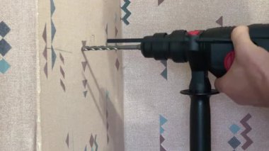 Elektrikli döner çekiçle beton duvarda delik açmak.