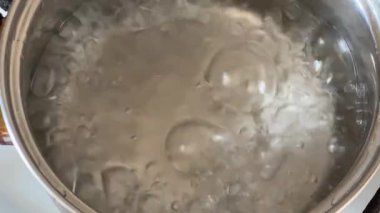 Ham donmuş kral karideslerini kaynayan suya atmak, yakın plan.