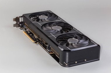 Masaüstü bilgisayarlarında kullanılan Gri arka planda ısıtıcı ve üç vantilatör ile donatılmış grafik kartı, seçici odak noktasında yakın plan