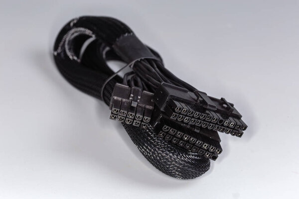 Internal power cable of a modular power supply unit of desktop computer in the metal shielding braided sleeving with corresponding connectors on a gray background, selective focus