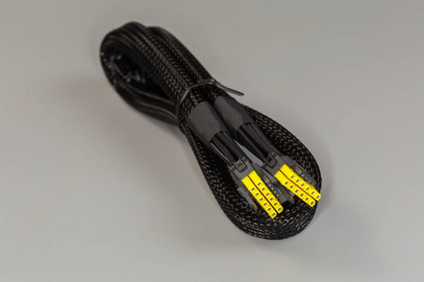 Internal power cable of a modular power supply unit of desktop computer in the metal shielding braided sleeving with corresponding connectors on a gray background, selective focus