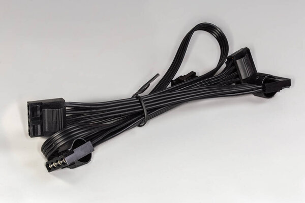 Internal detachable black multi-strand ribbon power cable of a modular power supply unit of desktop computer with corresponding connectors on a gray background