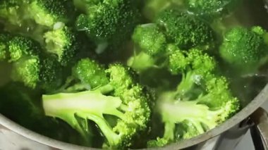Paslanmaz çelik tencerede pişerken taze brokoli dalları.