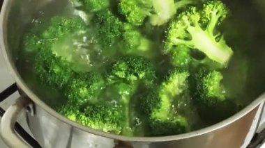 Paslanmaz çelik tencerede pişerken taze brokoli dalları.