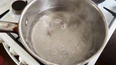 Ham donmuş kral karidesini kaynar suya yüklüyorlar.