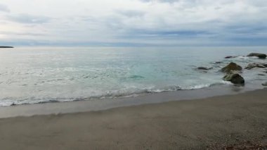 Kumsalda dalgalar akan kumlu ve taşlı deniz kıyıları