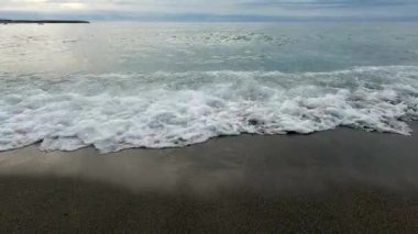 Sahildeki kumsalda dalgalar kıyıya vuruyor.