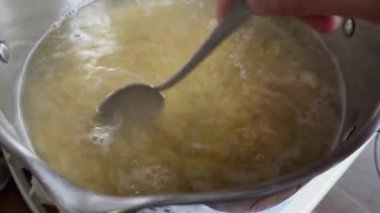 Kaynar suda kaşıkla makarna makarna karıştırmak.