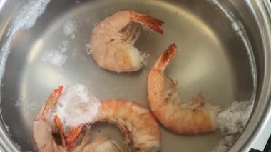 Kaynamış karides kuyruklarını plastik kaymak makinesiyle kaynar sudan çıkarıyorum.