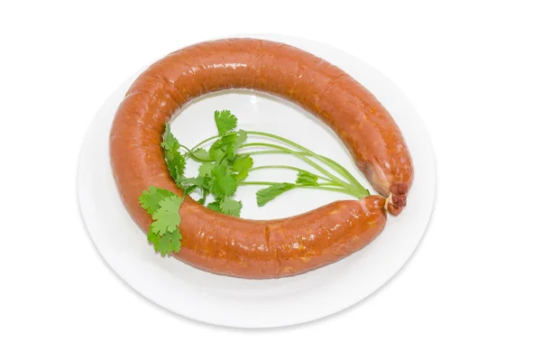 Sausage with branches of coriander on a light background — Zdjęcie stockowe