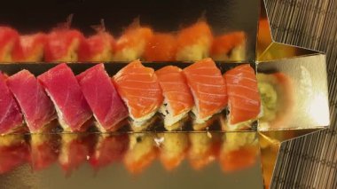 Suşi, somon balıklı uramaki ve altın ambalajlı ton balığı sarıyor.