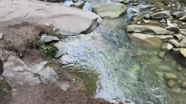 Dik kayalık kıyıları ve ahşap köprüsü olan dağ deresi