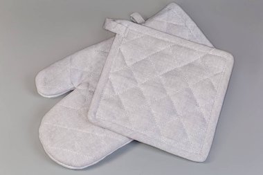 Açık gri örtülü tekstil fırın eldiveni ve gri arka planda kare tutacağı.