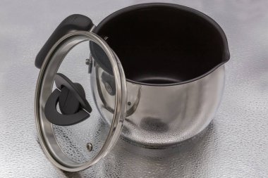 Küçük paslanmaz çelik tencere-kazan sopa olmayan iç yüzey, cam kapak ve gümüş bir yüzey üzerinde plastik saplar kaldırıldı