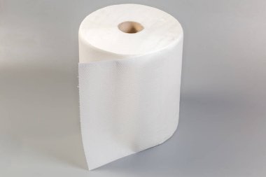 Gri bir yüzey üzerinde kabartmalı, yırtık dökük çarşaflı tek kullanımlık beyaz kağıt havluların rulosu.