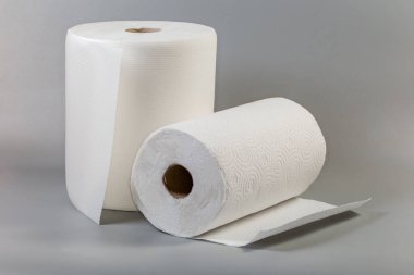 Gri bir yüzeye kabartmalı, yırtık dökük çarşaflı, tek kullanımlık beyaz kağıt havlulardan iki rulo.