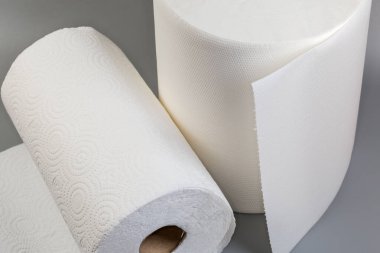 İki farklı rulo tek kullanımlık beyaz kağıt havlu ve kabartmalı yüzeyi yırtık pırtık, gri bir yüzeye yakın plan.