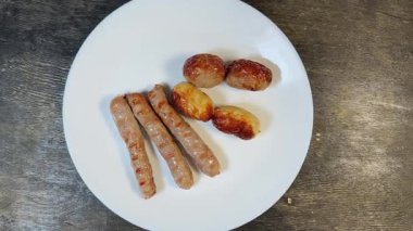 Siyah kırsal masada beyaz tabakta farklı ızgara sosisler.