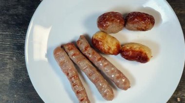 Beyaz tabakta farklı ızgara sosisler, yakın çekim.