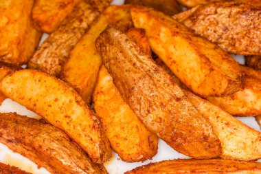 Tabaklarında farklı baharatlar, seçici bir odak noktasında yakın plan kesilmiş fırında patates parçaları.